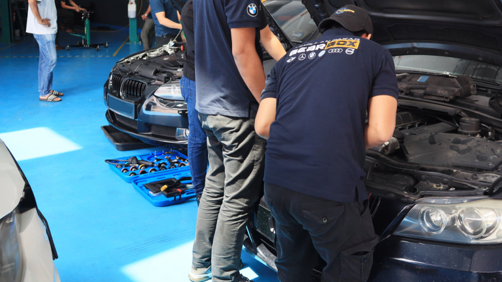 This image placed on (Pre Purchase Inspection). It shows a few personnel infront of the car during inspection and maintenance