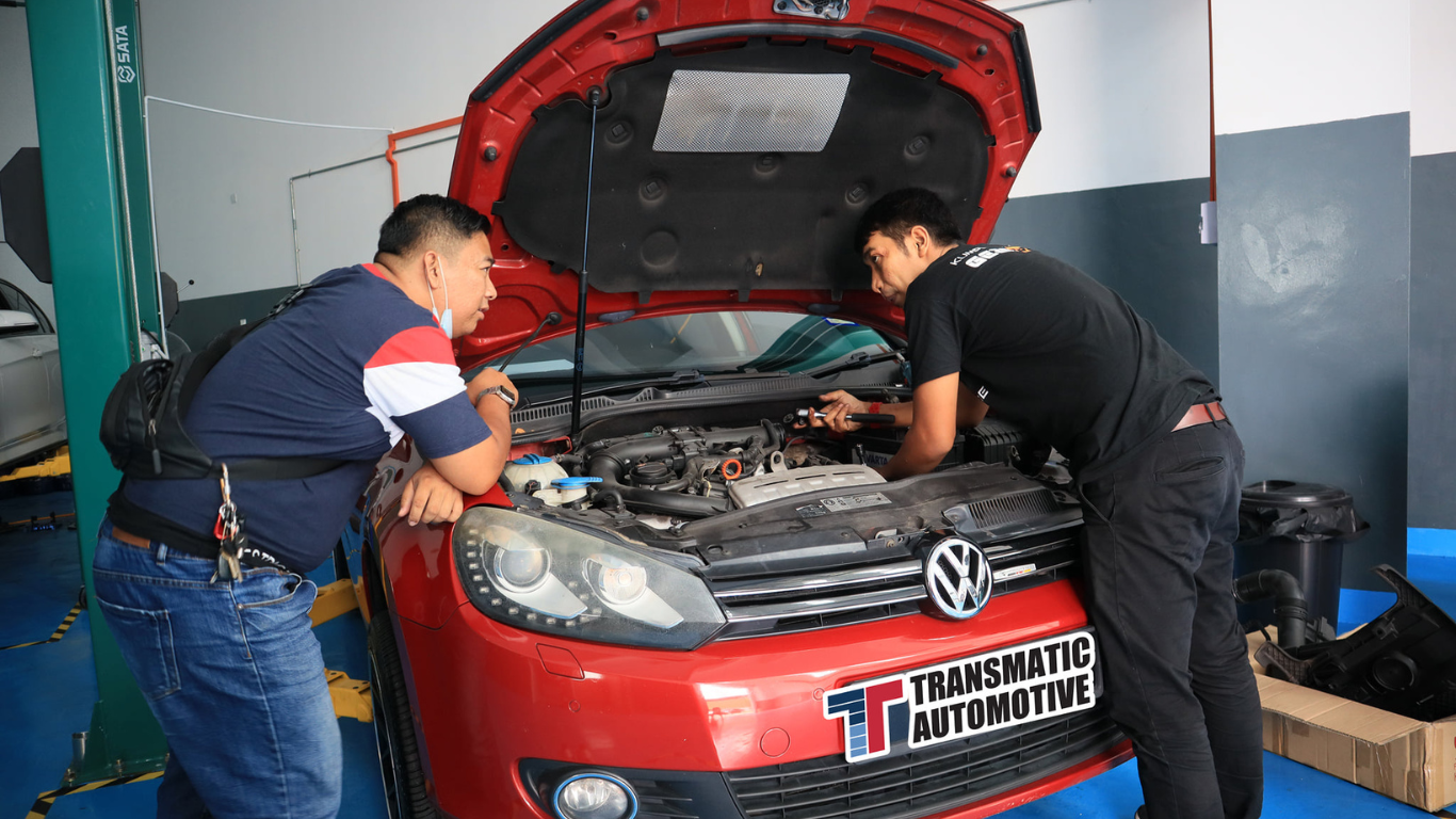 This image placed on (Pre Purchase Inspection). It shows 2 people infront of the car during inspectiuon and maintenance
